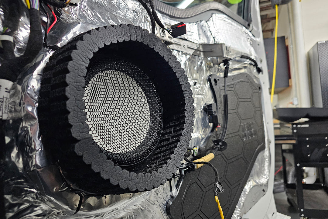 car door with door panel removed showing the inner door skin that is treated with ResoNix CLD Squares sound deadener and an Accuton Automotive C165AM 6.5" midbass speaker installed, and with ResoNix CCF Strips fast rings around them