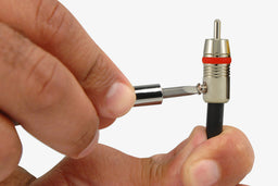 Person screwing in the set screw of a Planet Waves RCA end to attach to a dual coaxial cable
