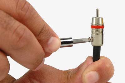 Person screwing in the set screw of a Planet Waves RCA end to attach to a dual coaxial cable