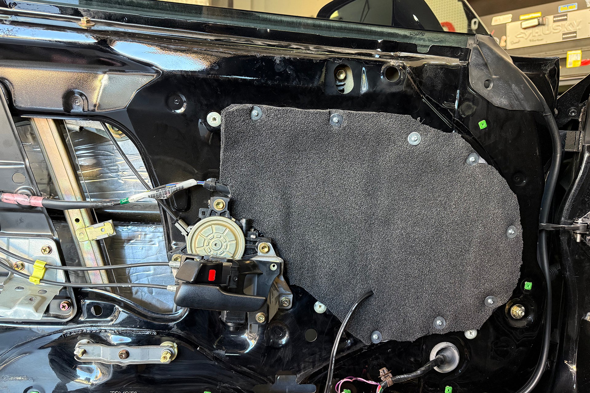 ResoNix Barrier being used to seal up access holes on the inner door skin of a vehicle. The outer door skin also has ResoNix CLD Squares automotive sound deadener mats applied.