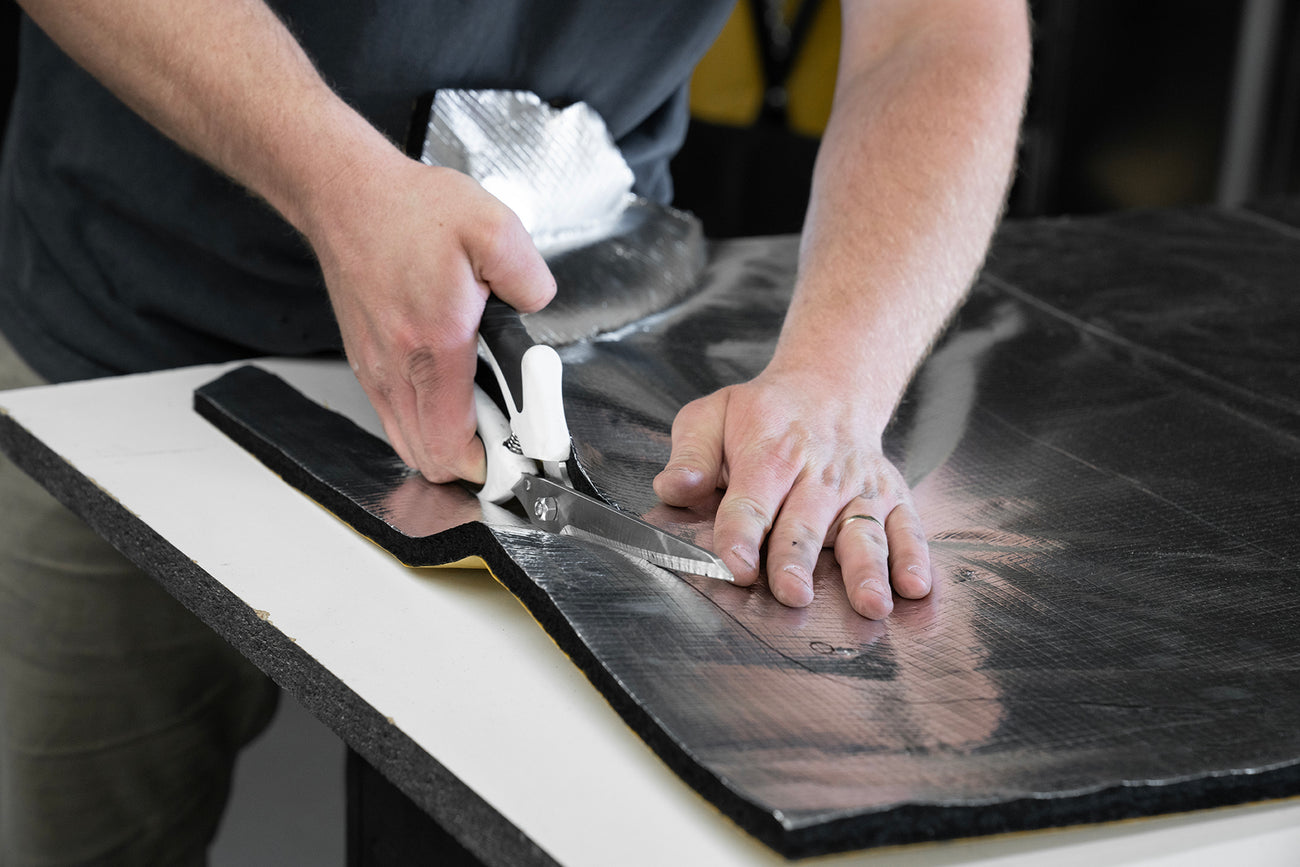 Close up shot of ResoNix Fiber Mat Silver sound insulation material being cut with shears