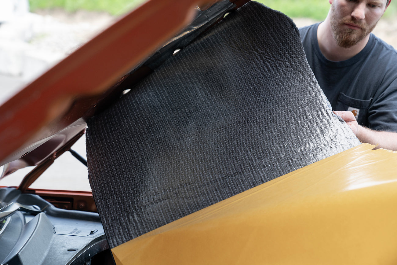 car hood being lined with ResoNix Fiber Mat Silver sound and heat insulation material showing the peel and stick adhesive