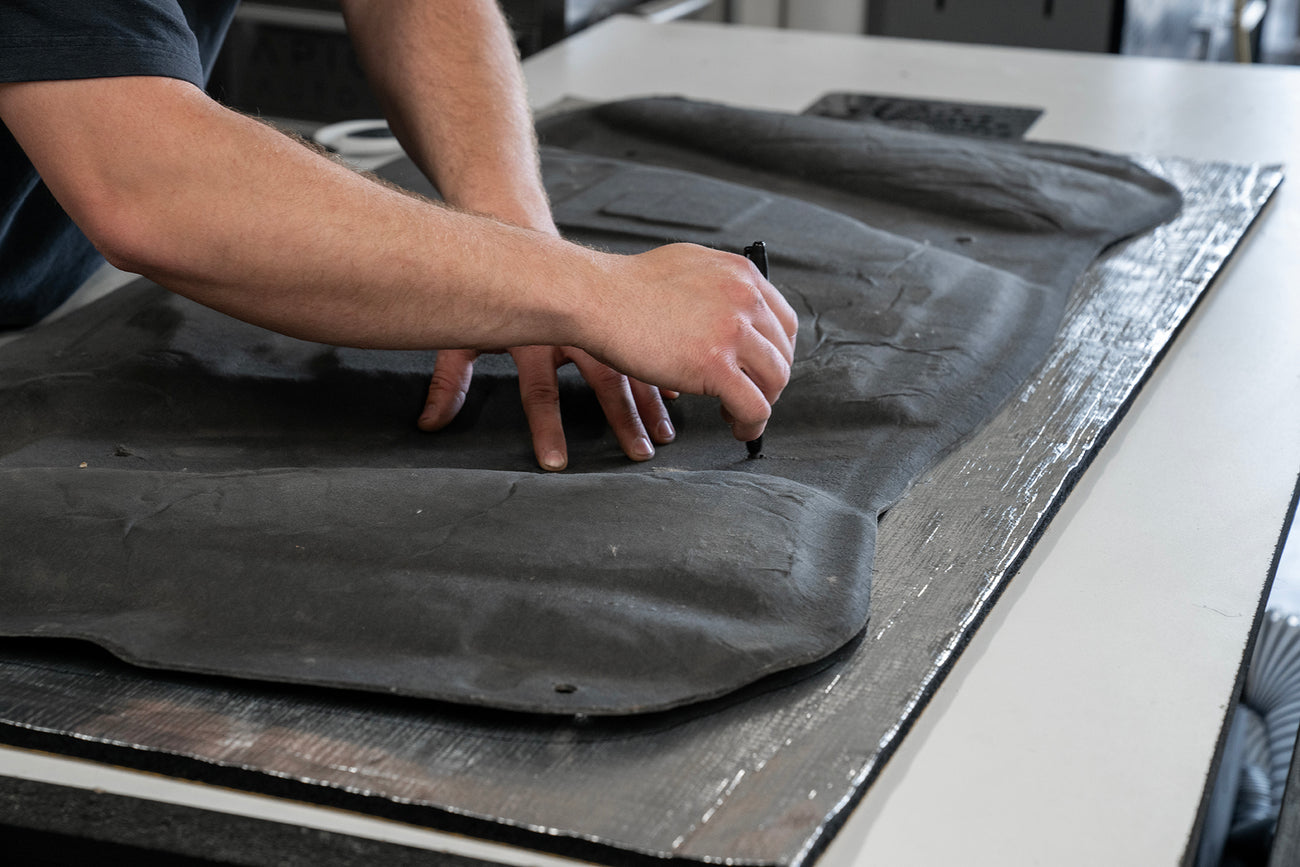 Close up shot of ResoNix Fiber Mat Silver automotive sound insulation and hood liner material being marked for cutting to shape