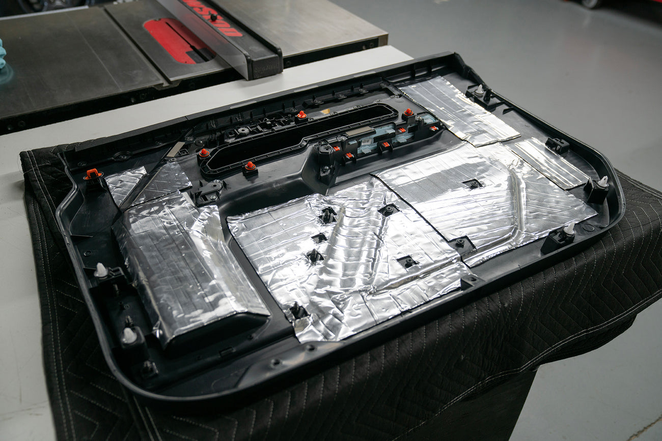 back side of a car door panel that has ResoNix CLD Squares sound deadener material applied to it