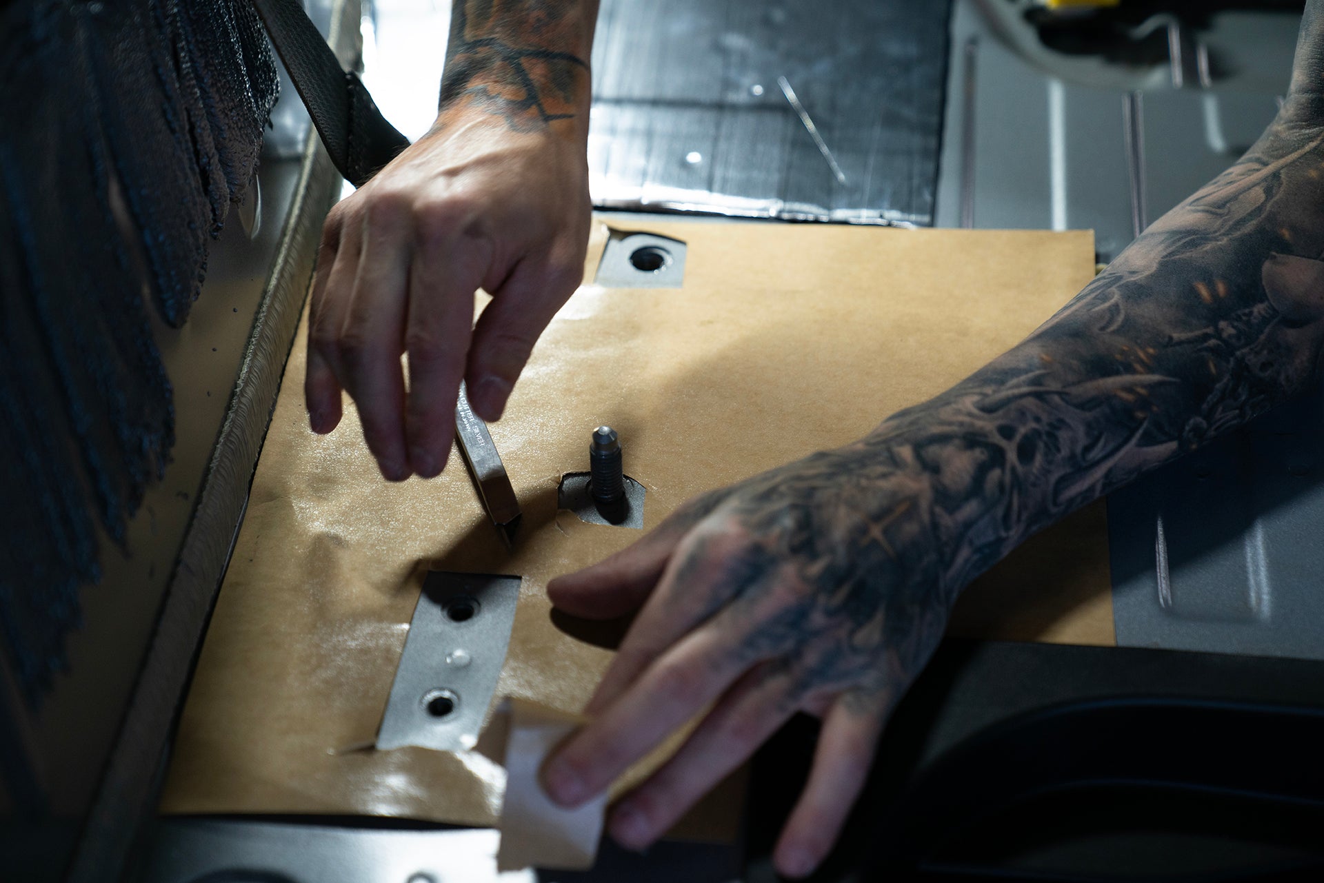 Someone in a Ford Bronco installing ResoNix Sound Solutions sound deadener close up