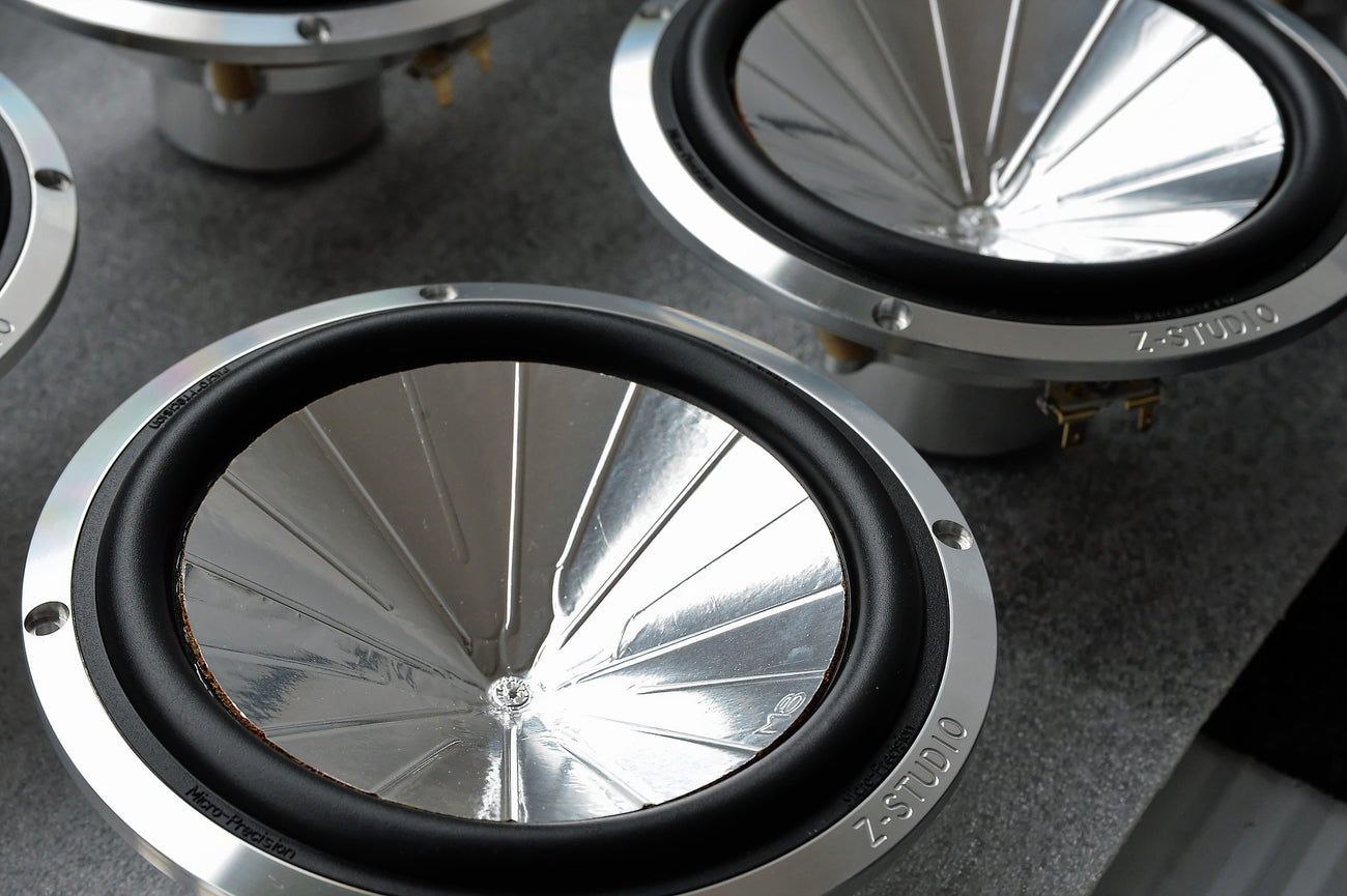 Close-up of speaker cones of the Micro precision Z-Studio 6.5" midbass speakers on a gray surface.