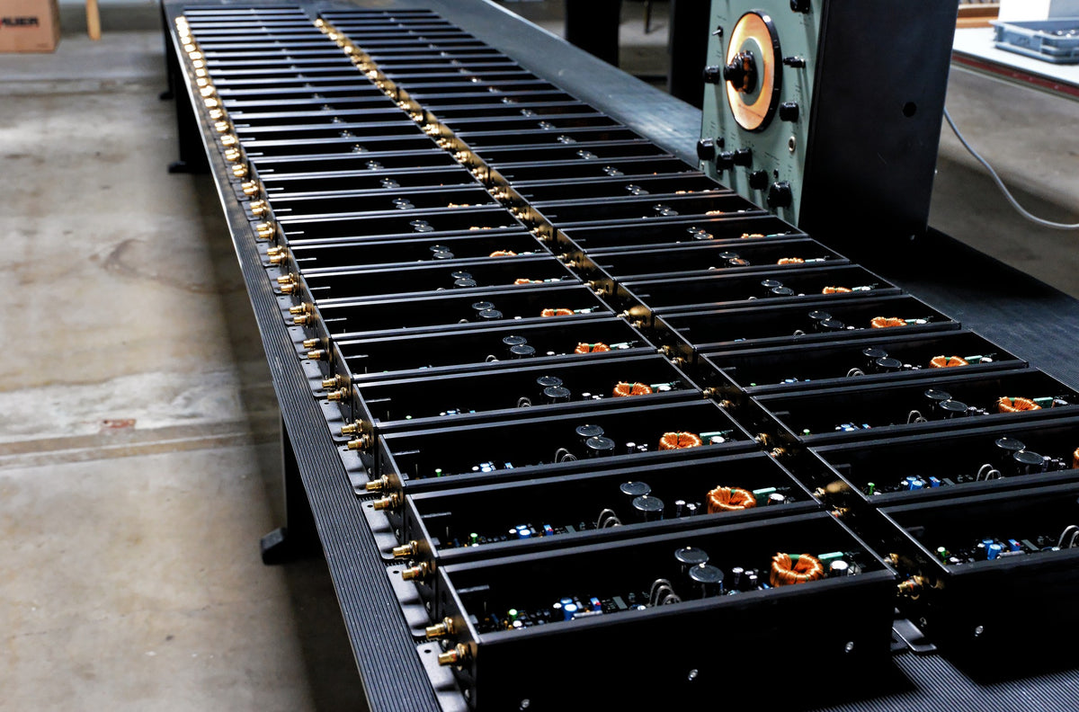 line up of many Micro Precision 5-Series two channel car audio amplifiers on a work table