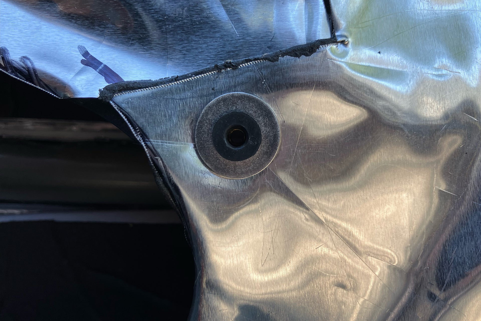 Up close photo of a well nut that it installed into the inner door skin that has ResoNix CLD Squares automotive sound deadening mats applied to the inner door skin.