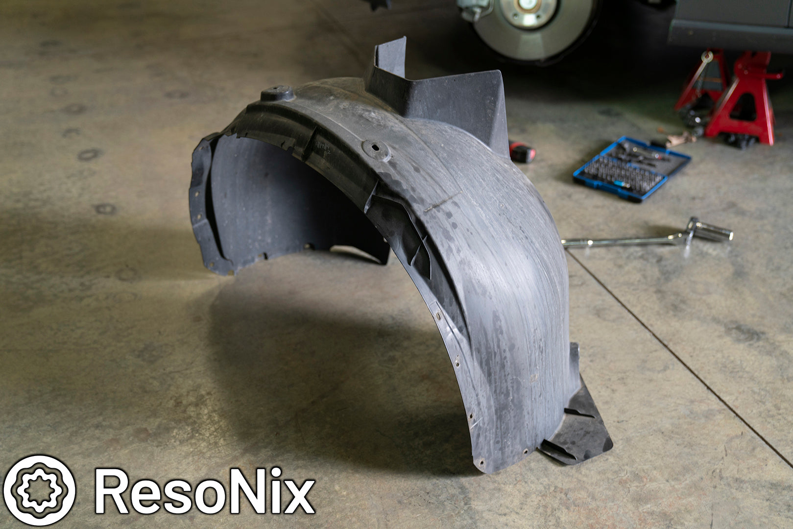 Car fender liner removed before installing ResoNix Sound Solutions CLD Squares sound deadening material and Fiber Mat to reduce wind, road, and tire noise